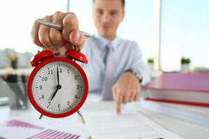 man hand red alarm clock stands desk office showing seven oclock am pm Master Time Management Skills with these 5 Proven Strategies.